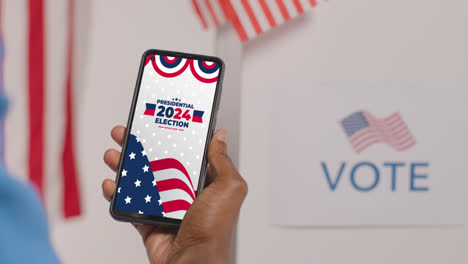 Nahaufnahme-Einer-Hand,-Die-Ein-Mobiltelefon-Mit-Bildschirm-Hält-Und-Die-Menschen-Dazu-Ermutigt,-Bei-Der-US-Präsidentschaftswahl-2024-Zu-Wählen-1